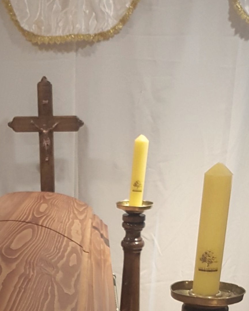 Sala de velatorio de Los Castaños con crucifijo y cirios con el logo de la funeraria